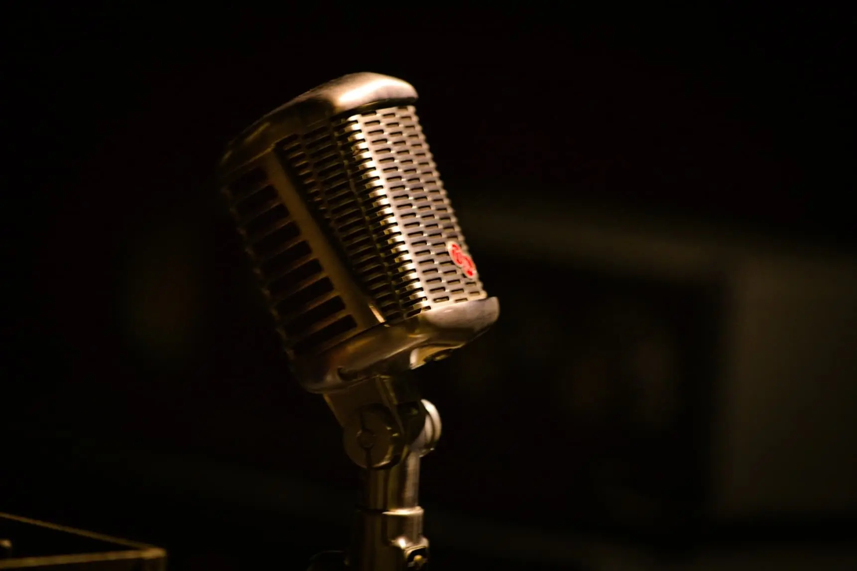 A vintage-style microphone is positioned on a stand against a dark, blurred background.